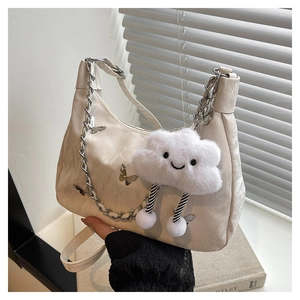 Detail of cream shoulder bag featuring silver butterfly charms and cloud plush pendant