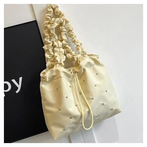 Detail view of cream white tote bag with cloud ruffled handles and rhinestone accents