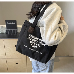Détail du sac cabas en toile avec poche latérale et finitions en cuir sur la bandoulière