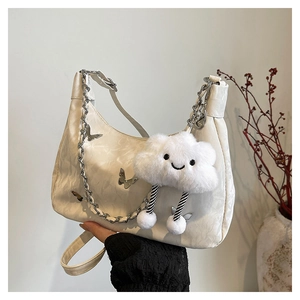Detail of white pleated tote bag featuring silver butterfly buckle and cloud plush charm