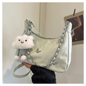 Detail of mint green half-moon bag with butterfly chain and plush cloud charm accessory