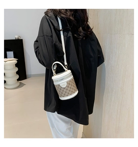 Detail of bucket bag with monogram pattern and white leather trim worn by model