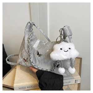 Macro detail of metallic silver shoulder bag with 3D butterfly charms and chain strap