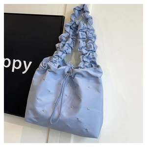 Detailed view of light blue pleated tote bag with sparkly rhinestones and drawstring closure
