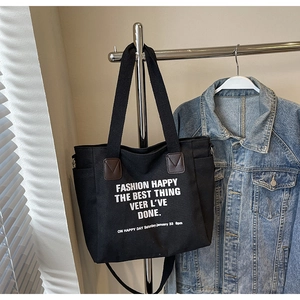 Détail du grand sac cabas en toile noire avec texte blanc et patch en cuir marron