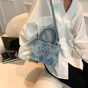 Blue denim crossbody bag with quilted fringe texture and golden hardware accents