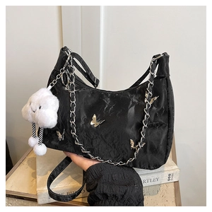 Detail of black nylon shoulder bag with silver butterfly appliques and metal chain decor