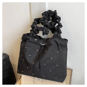 Detail of black pleated handle tote bag with metallic stud accents and drawstring closure