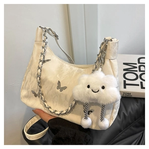 Detail of cream white underarm bag with butterfly buckle and plush cloud charm