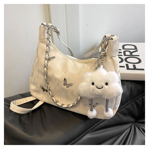 Detail of cream shoulder bag with silver butterfly chain and plush cloud charm