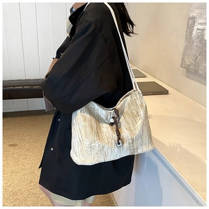 Detailed close-up of textured tote bag featuring pleated fabric and dark braided drawstring