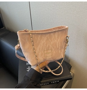 Détail du sac bandoulière plissé rose avec chaîne dorée et texture d'étiquette de marque
