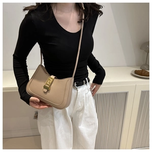 Détail d'un sac en cuir beige minimaliste avec boucle géométrique dorée et bandoulière