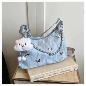 Détail du sac sous le bras plissé bleu clair avec papillons argentés et peluche nuage blanc