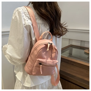 Vue latérale détaillée d'un mini sac à dos en nylon rose porté par un mannequin chic