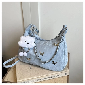 Détail du sac bandoulière plissé bleu clair avec papillon argenté et breloque nuage