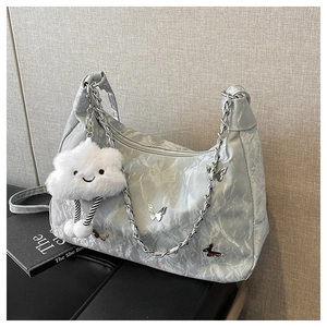 Gros plan d'un sac à main plissé argenté avec breloques papillon et pendentif nuage
