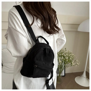 Vue arrière d'un mannequin portant un mini sac à dos noir en nylon au design minimaliste