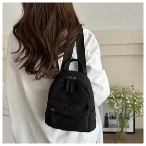 Mini sac à dos en nylon noir porté par un mannequin avec poche zippée et bretelles