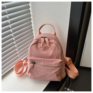 Detailed macro view of pink nylon mini backpack on windowsill with natural sunlight