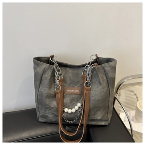 Detail of vintage canvas tote with silver chain, pearl charm and leather logo patch