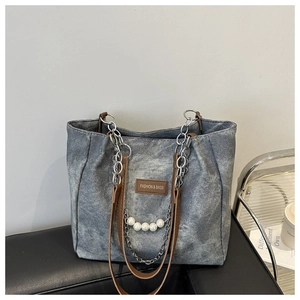 Detail of denim shoulder bag with brown leather label and stylish pearl chain strap