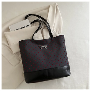 Detail of red heart patterns on grey canvas tote bag with a metallic silver bow clasp