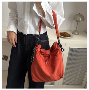 Detailed shot of an orange canvas tote bag with contrast rope handles and metal snap buttons