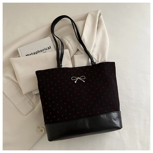 Close-up of heart pattern tote bag featuring leather base and silver metal bow detail