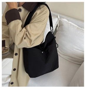 Detail of black nylon shoulder bag with woven rope strap on khaki trench coat model