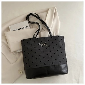 Detailed view of grey tote bag with polka dots, bow embroidery, and silver bow hardware