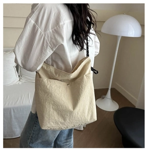Detail of beige canvas hobo bag with metal buckle pocket and woven strap on model