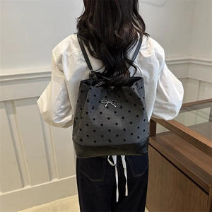 Gray polka dot tote bag with leather patchwork and silver bow accessory shown on model