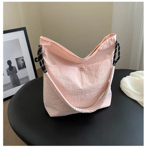 Close-up of pink nylon tote bag with crinkled texture and black and white rope handle