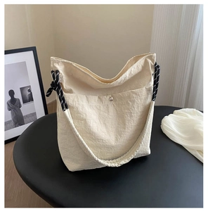 Detail of beige canvas tote with a silver snap pocket and woven cord handle