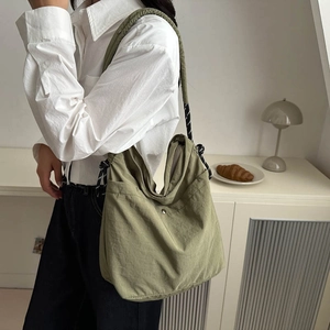 Olive green minimalist shoulder tote bag with cord strap shown on model in a soft room