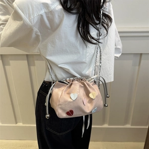 Pink drawstring bucket bag with colorful heart patches and silver chain strap