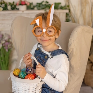 Close-up of child wearing orange glitter Easter bunny glasses with white pom-pom detail