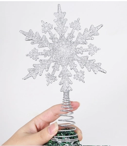 Close-up of a silver glitter snowflake Christmas tree topper with a spiral spring base