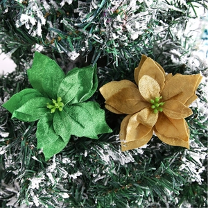 Close-up of artificial emerald green and gold poinsettia flowers on a snowy Christmas tree