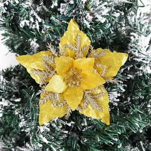 Golden glitter poinsettia flower ornament on snow-covered Christmas tree branch