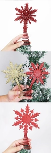 Close-up of snowflake Christmas tree toppers in red, gold, and silver with glitter finish