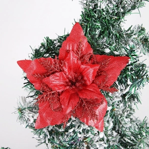 Close-up of artificial red glitter poinsettia flower on a snowy Christmas tree branch