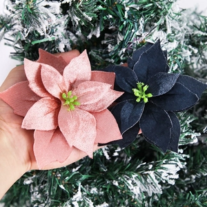 Close-up of pink and navy velvet poinsettia flowers on a snowy Christmas tree