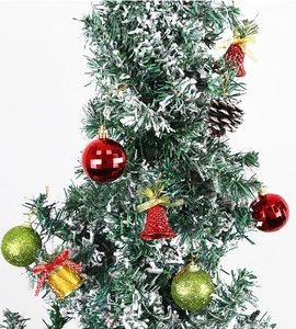 Gros plan de boules à carreaux rouges, cloches et pommes de pin sur un sapin enneigé