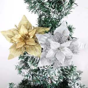 Close-up of sparkling gold and silver glitter poinsettia flowers on a snowy Christmas tree