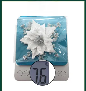 Detailed view of a white glitter artificial poinsettia flower in a clear package, 7.6g