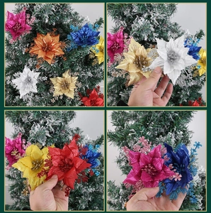 Close-up of glittered poinsettia ornaments on a snow-covered Christmas tree detail