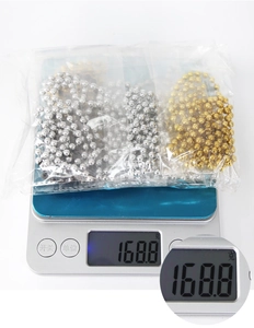 Bulk gold and silver plastic bead chains in clear packaging being weighed for shipment