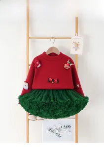 Detailed view of red Christmas sweater with 3D Santa and green tulle skirt on a rack